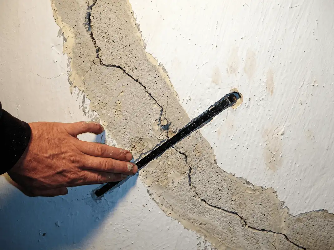 A wall with a large crack is being inspected by a professional in Shreveport, LA